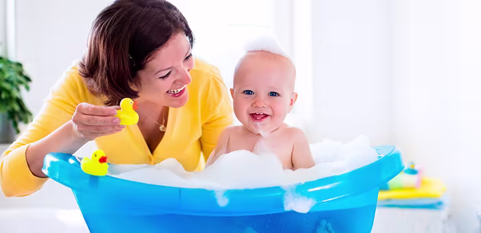 Mamá bañando a su guagua en bañera de bebé.