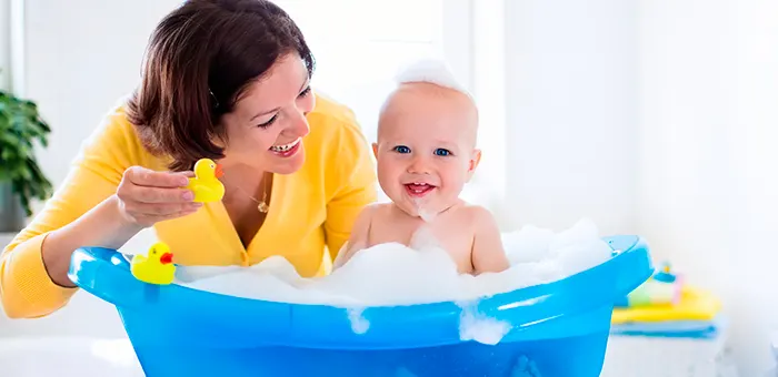 Mamá bañando a su guagua en bañera de bebé.