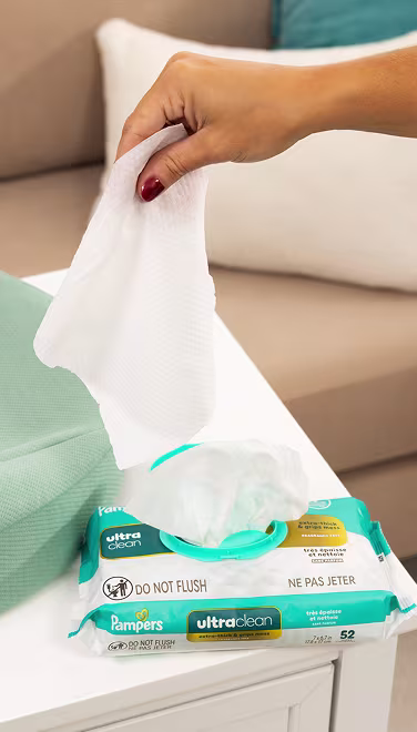 Mom pulling an ultraclean wipe out of the fitment sitting on a changing table