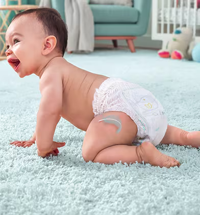 Uśmiechnięte i raczkujące dziecko w pieluszce Pampers. Uśmiechnięte i raczkujące dziecko w pieluszce Pampers.