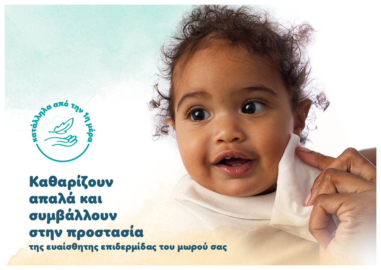 Σε ένα μωράκι ένα χέρι ακουμπάει ένα μωρομάντηλο στο αριστερό του μάγουλο. Αναγράφονται τα κείμενα: «Καθαρίζουν απαλά και συμβάλλουν στην προστασία της ευαίσθητης επιδερμίδας του μωρού σας και Κατάλληλα από την πρώτη μέρα».
