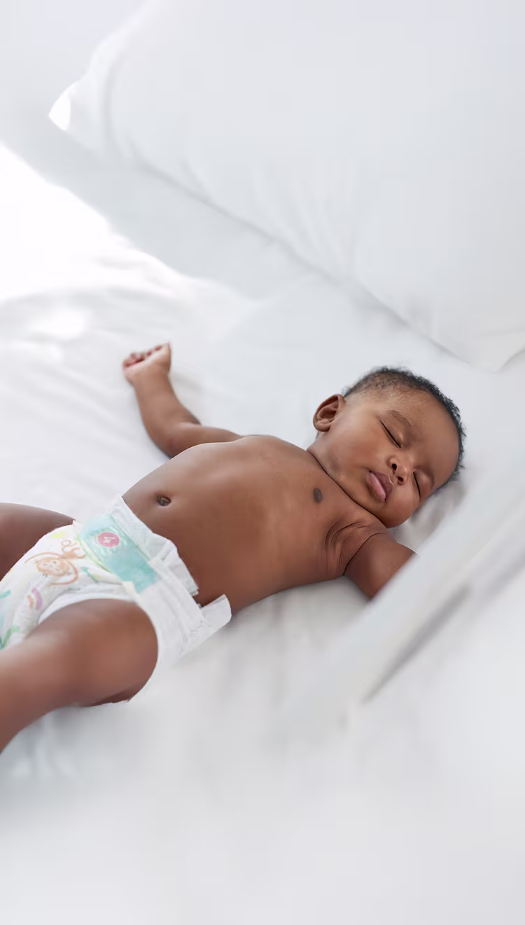 Ein Baby schläft auf dem Rücken und trägt eine Pampers Baby-Dry Windeln.