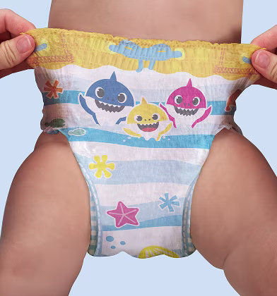 Um par de mãos estica os lados de uma fralda de natação com tema do Baby Shark na parte inferior de um bebé, mostrando a cintura elástica e o design completo. Um par de mãos estica os lados de uma fralda de natação com tema do Baby Shark na parte inferior de um bebé, mostrando a cintura elástica e o design completo.
