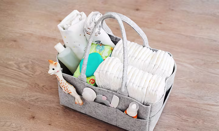 Image of a diaper caddy basket organized with diapers, wipes, and other diapering essentials in compartments.