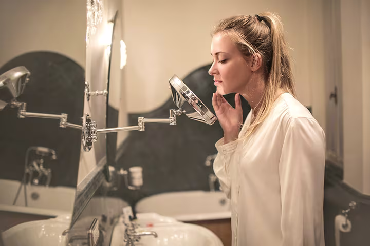 Γυναίκα περιποιείται το πρόσωπό της, μπροστά από καθρέφτη