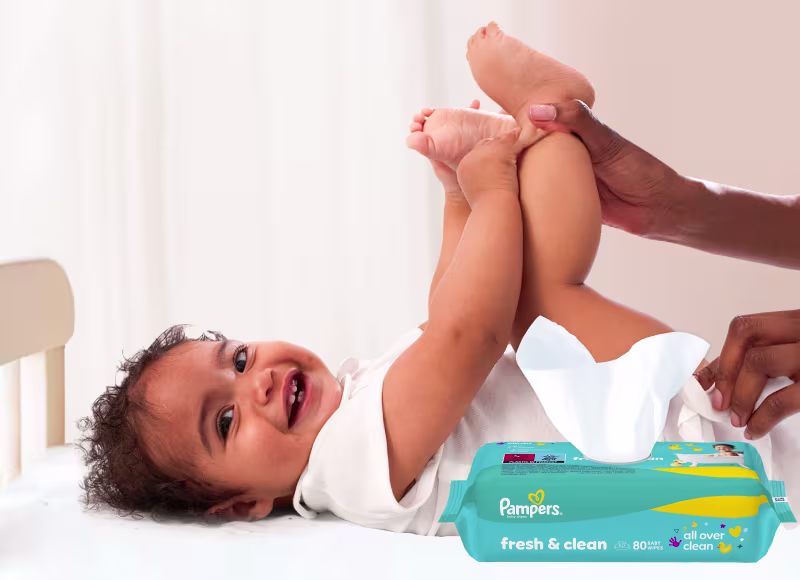 Baby liegt auf dem Rücken und wird sanft mit einem Feuchttuch gereinigt.