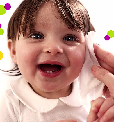 Un gros plan du visage d’un bébé, tandis qu’une main nettoie doucement la joue avec une lingette Pampers Fresh & Clean.