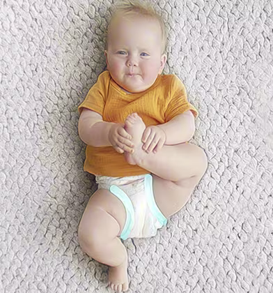 Un bebeluș în scutec stă pe spate, ținând un picior cu ambele mâini și privind în sus spre cameră cu un zâmbet ușor. Un bebeluș în scutec stă pe spate, ținând un picior cu ambele mâini și privind în sus spre cameră cu un zâmbet ușor.