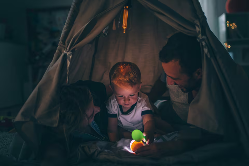 Baby smiling and laughing while lying in a soft white hammock swing. Isolated on black background.