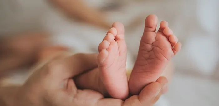 Mamá sosteniendo pies de bebé prematuro Mamá sosteniendo pies de bebé prematuro