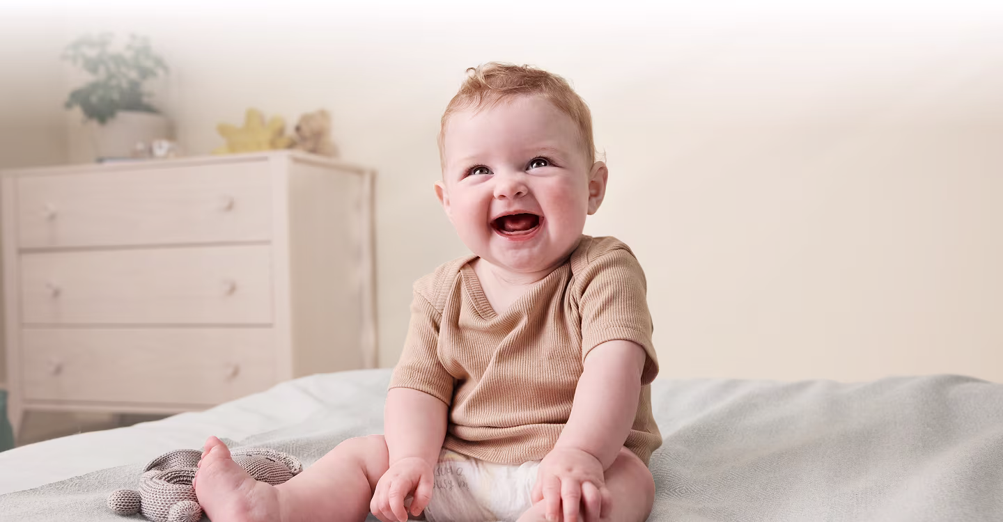 Χαμογελαστό παιδί στο κρεβάτι με πάνα Pampers