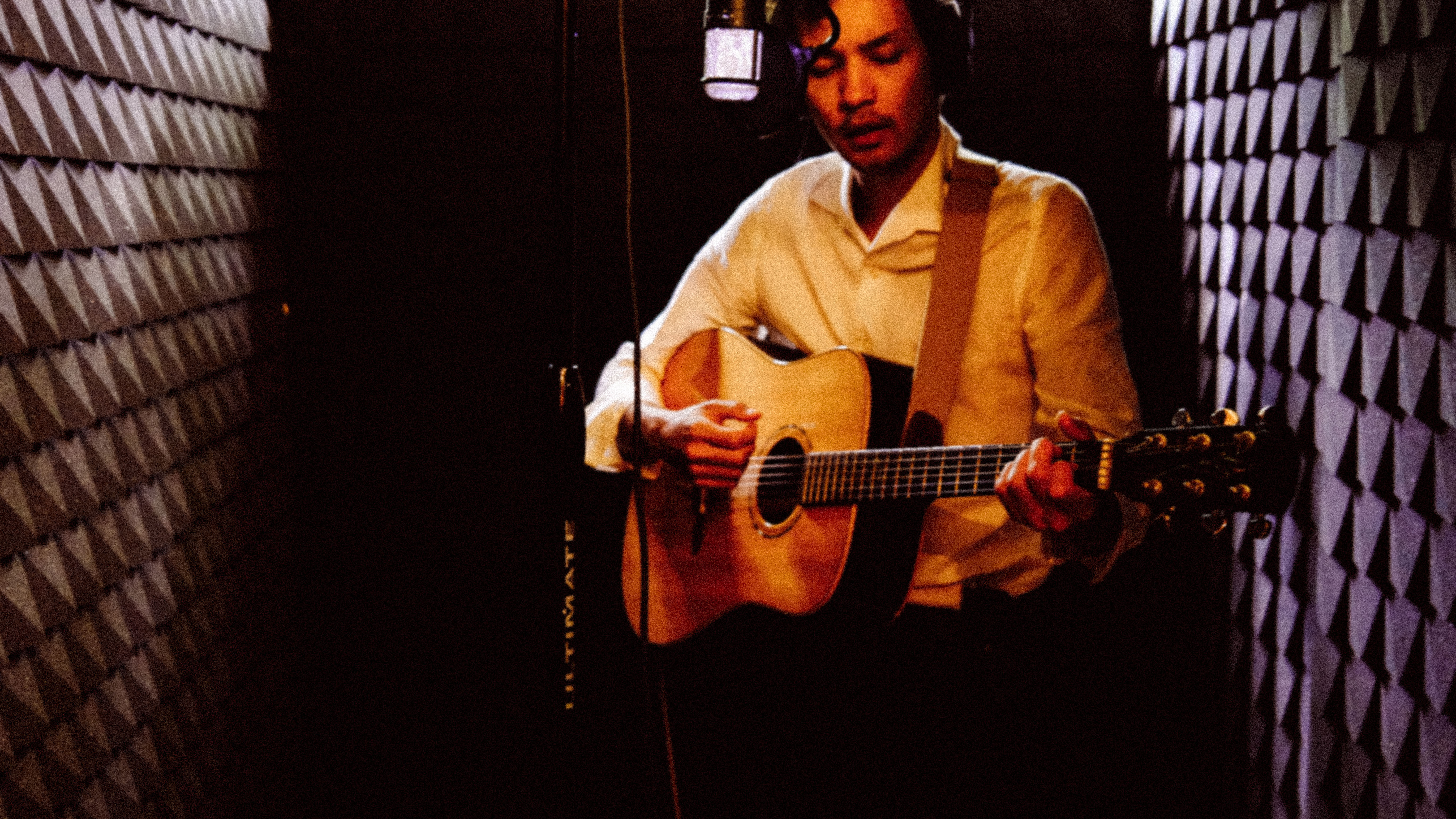 Musician playing guitar in recording booth