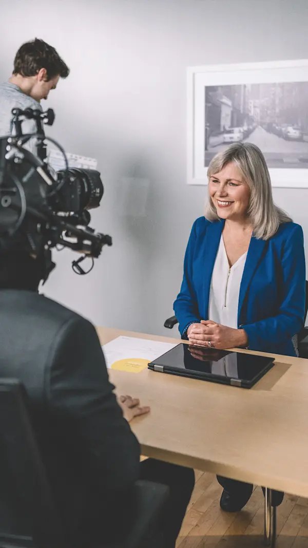 Over-the-shoulder view of the helmet rig as an actor smiles across a desk in an office set.