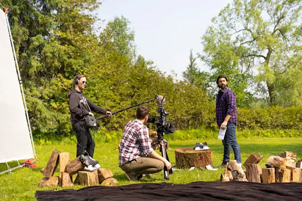Crew filming an actor in a purple plaid shirt beside stacked firewood for the Fairstone campaign