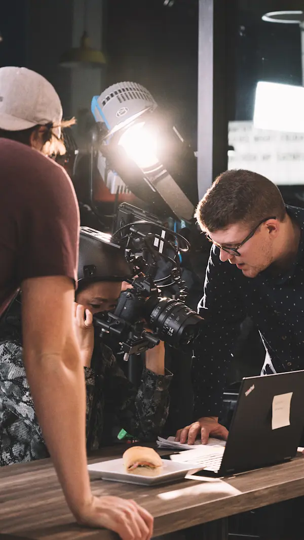 Director pointing at a laptop as an actor in the helmet rig films the screen under a studio light.