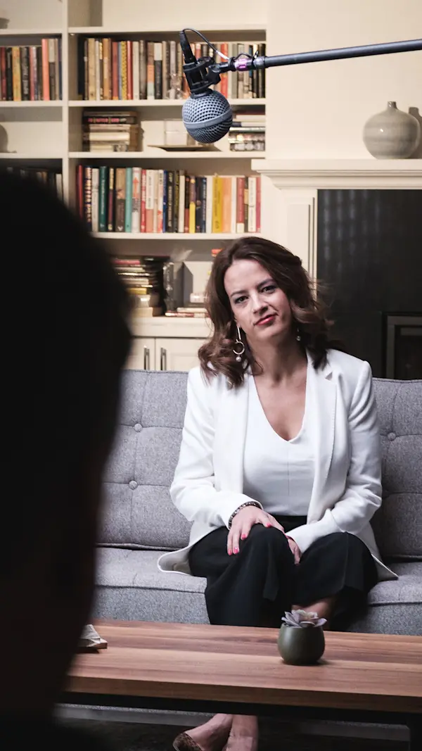 Financial advisor seated on a grey couch listening to a question, with a boom microphone overhead