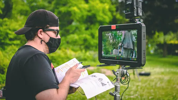 An Oak + Rumble director holds storyboards and a shot list beside an on-set monitor showing the playground.