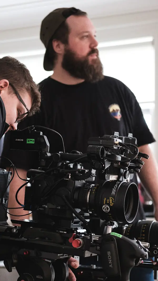 Cinema camera with a large prime lens being prepped on set, with crew members working behind it