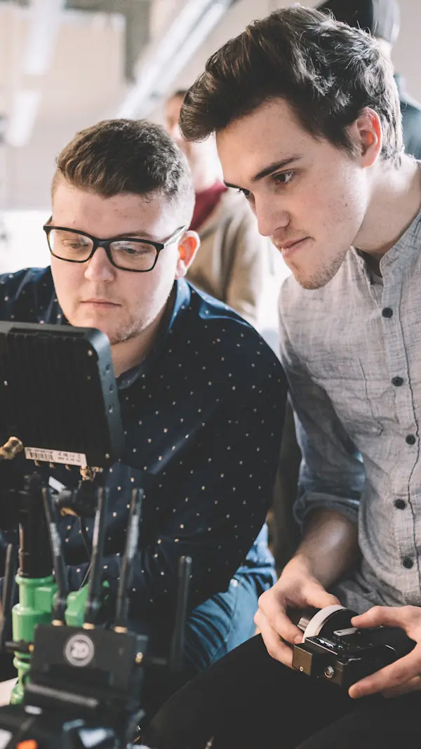 Two crew members watching a monitor while one pulls focus with a wireless remote.