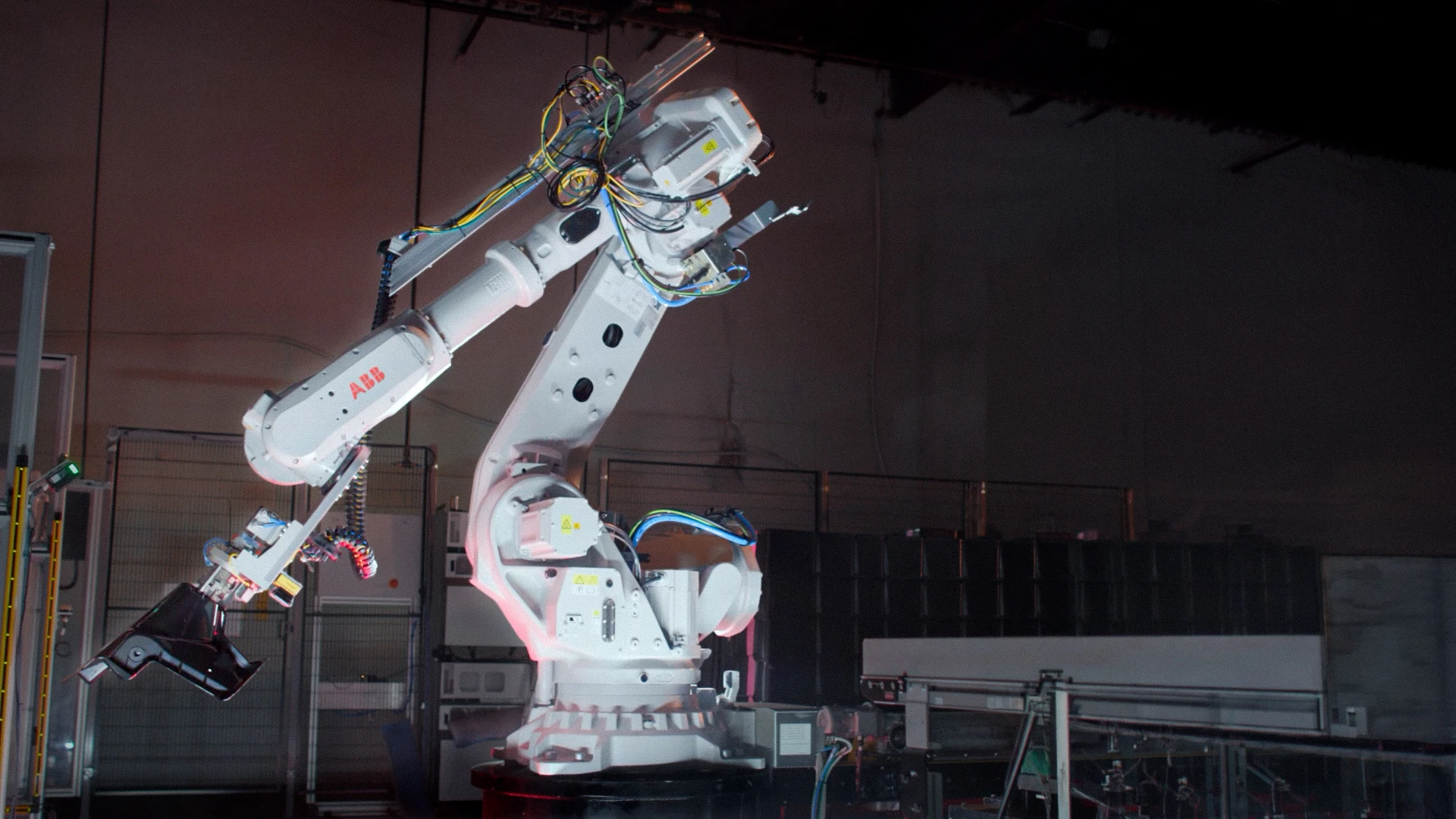 Industrial robot arm lit against a dark factory floor in 2CM Innovative's sales video