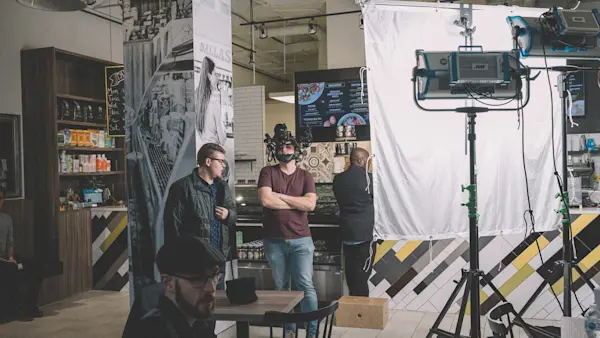 Crew waiting between takes in a juice bar, with lights and a diffusion frame set up by the counter.