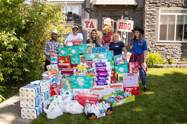 Volunteers pose with a large pile of donations with signs reading YA HOO