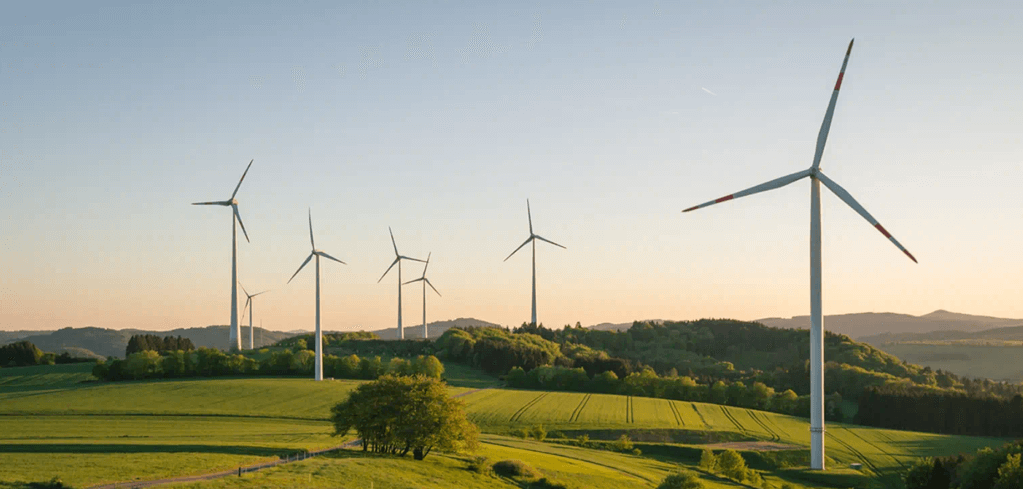 Wind turbines on rolling green hills against a sunset sky, showcasing renewable energy in a rural landscape.
