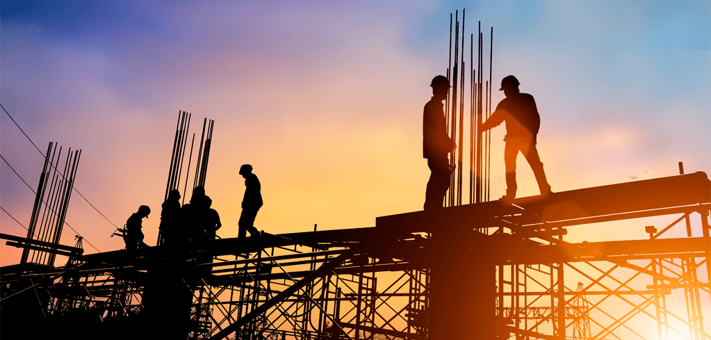 Silhouettes of construction workers on scaffolding with steel rebar against a colorful sunset sky.