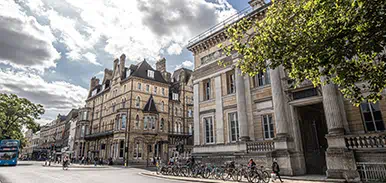 Historic stone buildings along a European street with ornate architecture under partly cloudy skies.