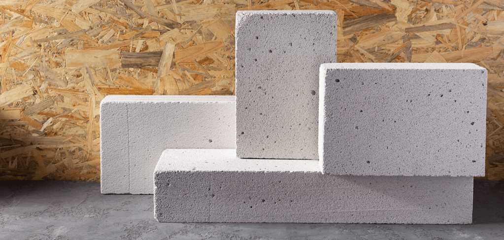 Blocks of reinforced autoclaved aerated concrete arranged in a geometric pattern against a wooden particle board background.
