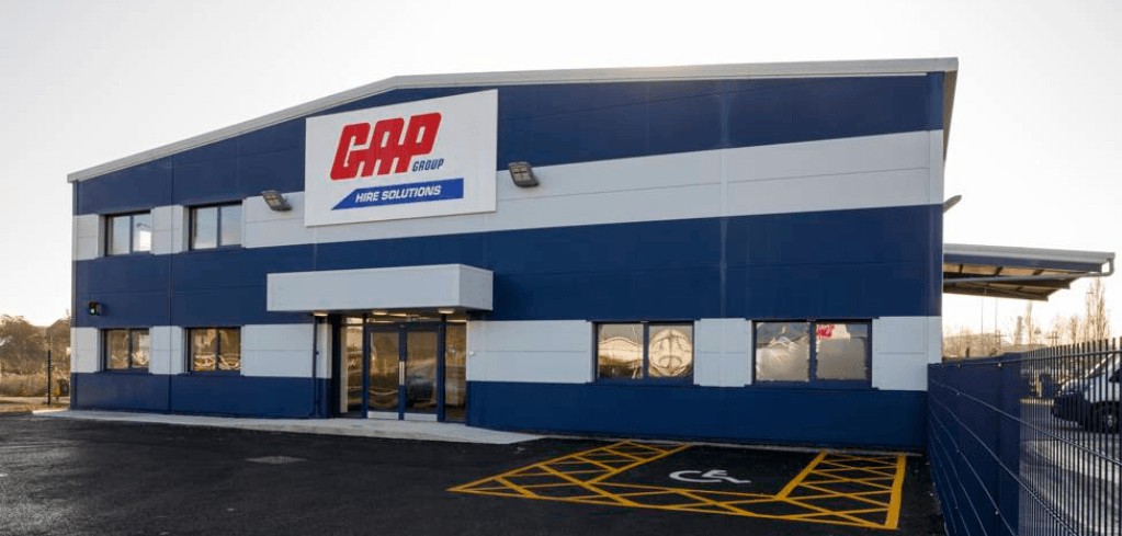 Exterior of a GAP Group Hire Solutions building with blue and white facade, parking lot, and accessible parking space.