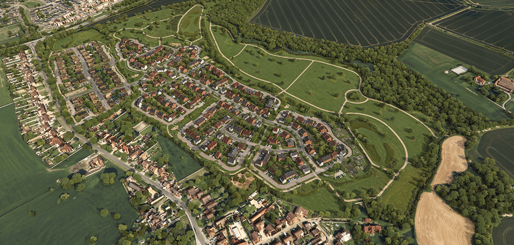 Aerial view of a residential housing development with red-roofed homes, tree-lined streets, green parkland, and surrounding farmland.