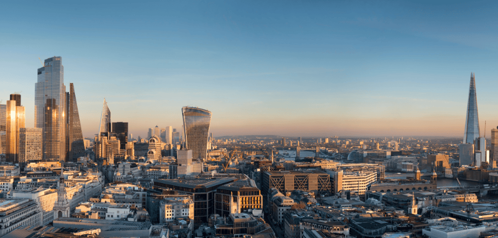 London skyline at sunset featuring iconic skyscrapers including the Shard and Walkie-Talkie building under clear blue sky.