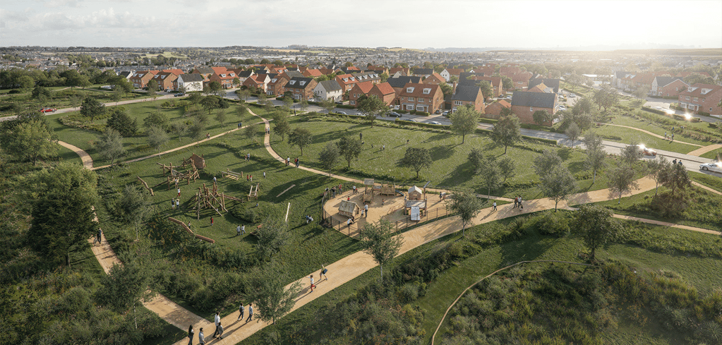 Aerial view of a green residential neighborhood with a playground, winding paths, trees, and red-roofed houses in the background.