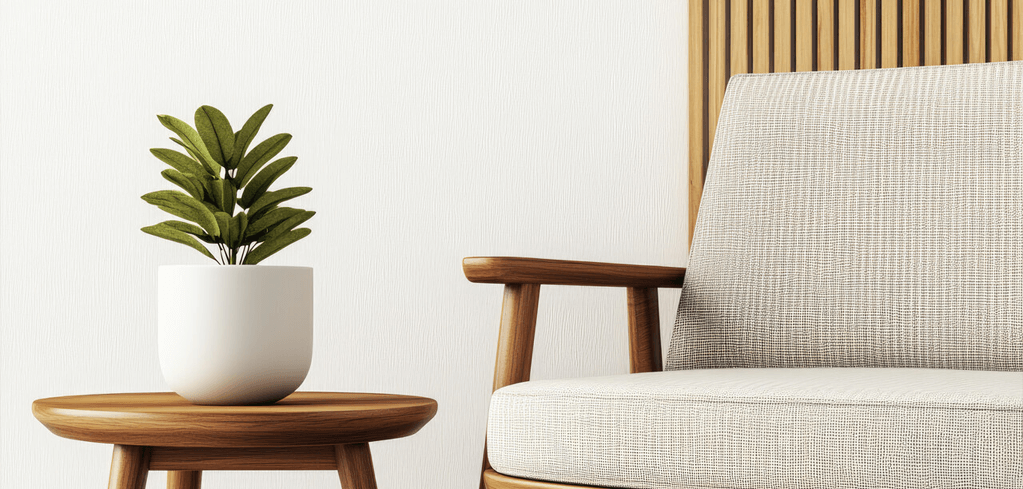 Modern living room corner with beige armchair, wooden side table, and green plant in white pot against textured wall.