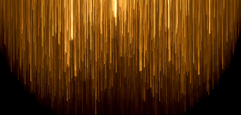 Cascading golden light streaks against dark background, creating a shimmering curtain-like effect.