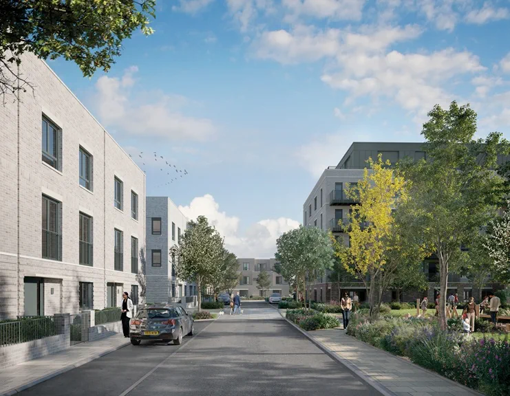 Modern residential development with white apartment buildings, tree-lined street, and landscaped gardens under blue sky.