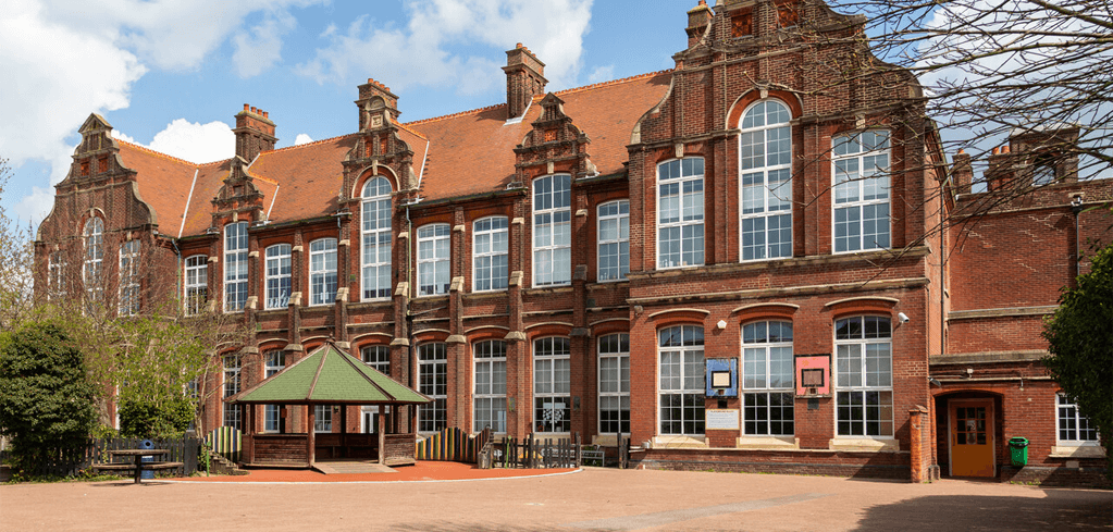 Historic red brick building with ornate Dutch-style gables, large windows, and a green-roofed pavilion in the courtyard.