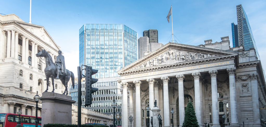 Bank of England building with equestrian statue in London's financial district, modern skyscrapers in background.