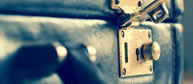 This image features a close-up of a vintage leather briefcase with a brass lock and keyhole detail, highlighting its craftsmanship and timeless character. The worn leather texture and antique hardware evoke a sense of reliability, security, and classic professional style. 