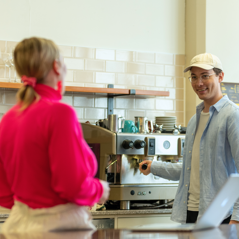 Man and woman smiling at each other while making a coffee