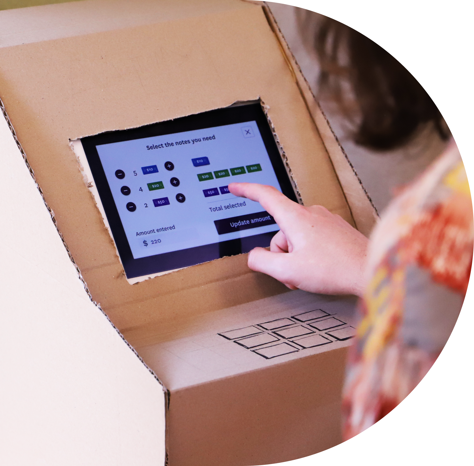 Rounded image of a user using the Westpac smart ATM framed by a cardboard model of an ATM.