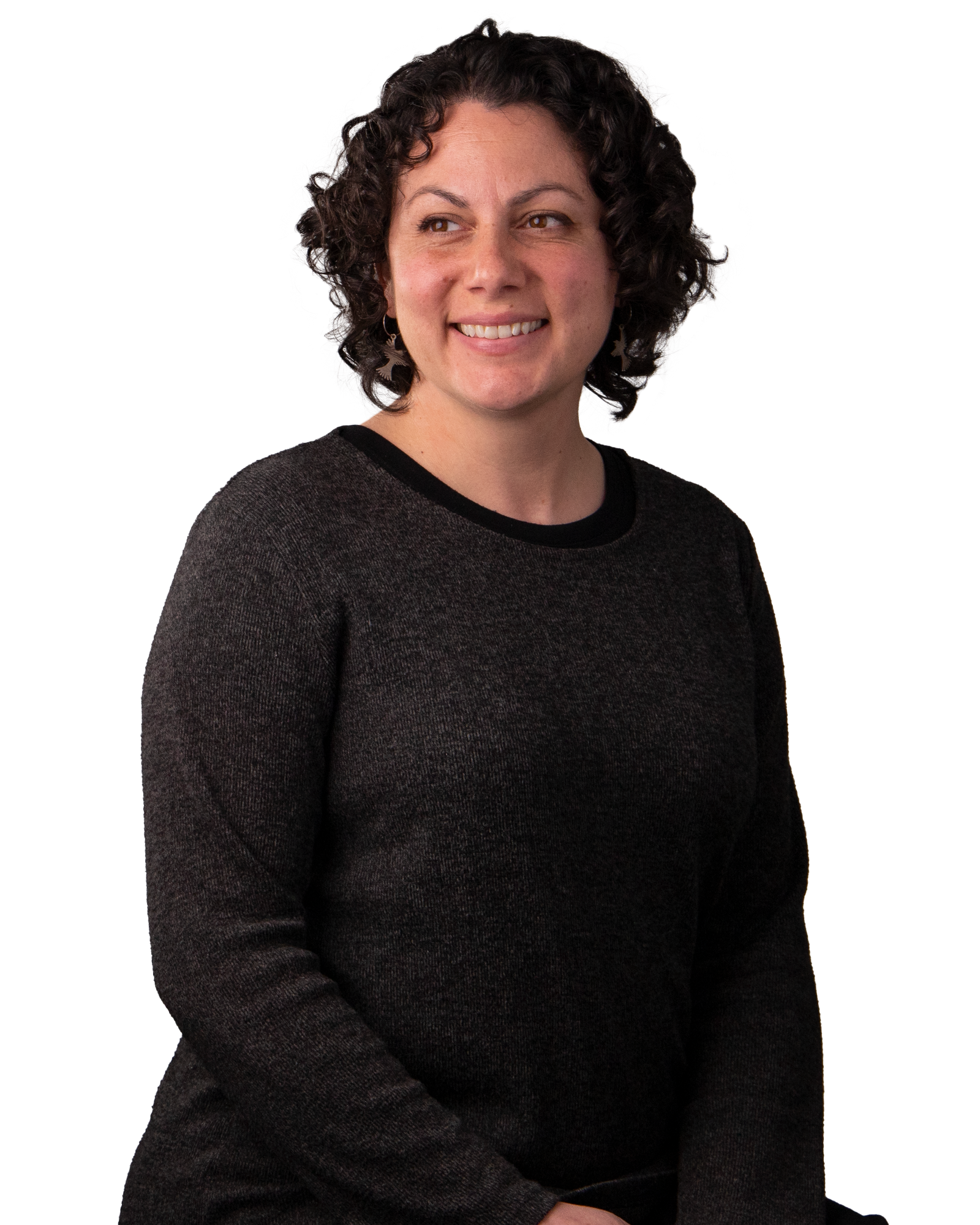 Women with dark curly hair. Wearing a black, long sleeve top, Smiling.