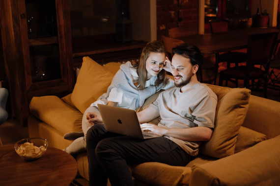 dellent casal sentado no sofá a olhar para um computador a trabalhar