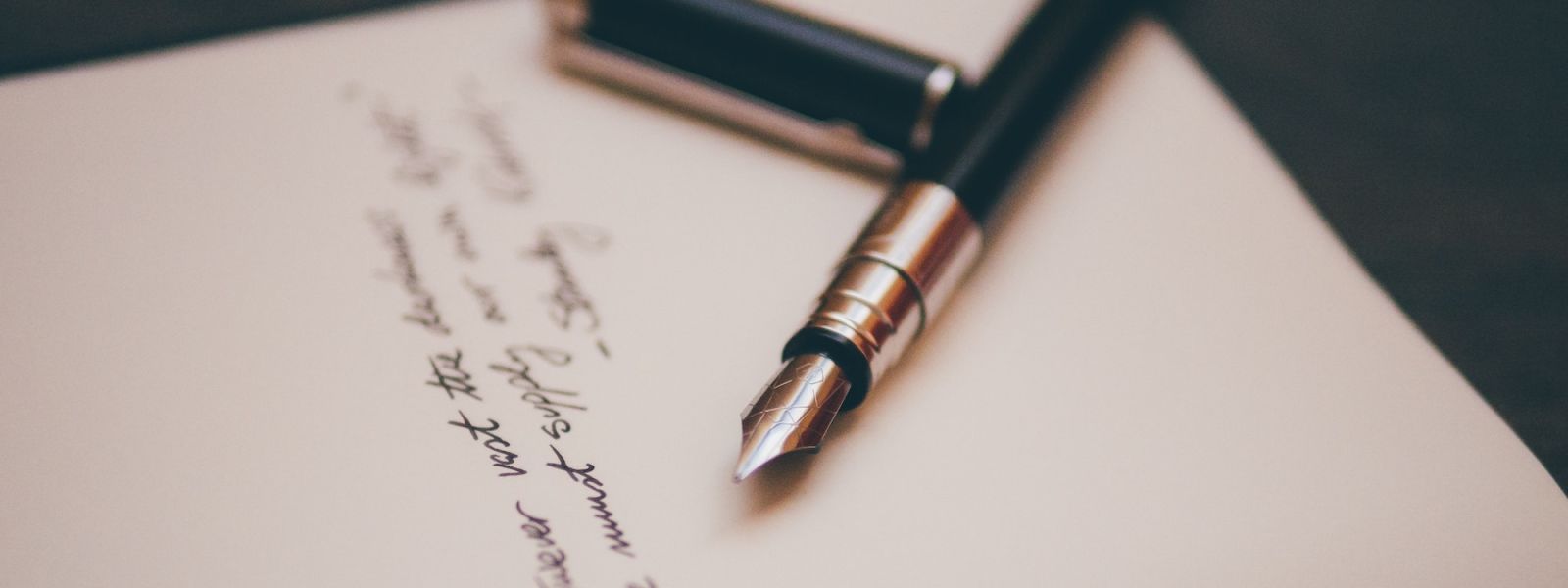 A fountain pen lying on a handwritten letter.
