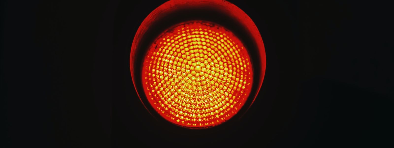 A red traffic light with a completely black background.