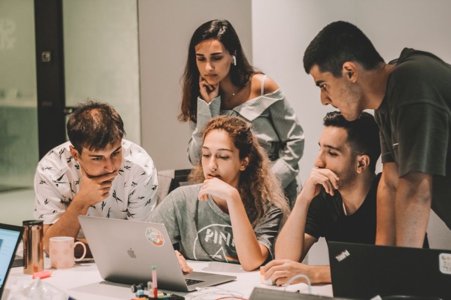 A group of 5 people looking at a laptop screen.