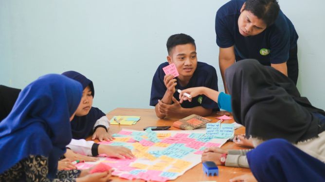 A group of people huddled around a table pull of coloured sticky notes.