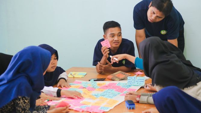 A group of people huddled around a table pull of coloured sticky notes.