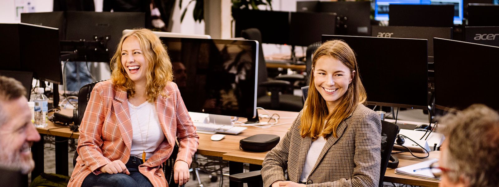 Amelia and Sarah from the Karbon team are smiling at work desks, mid-discussion with Stuart and Ian.